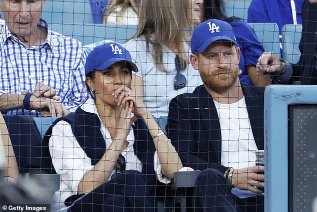 Prince Harry and Meghan Markle’s style statement: Couple deliver subtle message of unity as they ‘mirror’ each other at A-list baseball game – as Royal Family’s battles continue